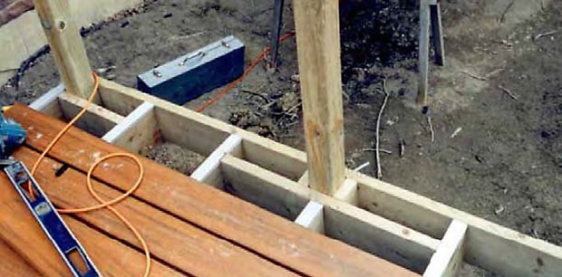 Rail post secured with blocking where a joist interferes with position.