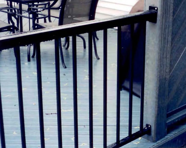 Aluminum railing attached to a privacy screen using wall mount brackets.