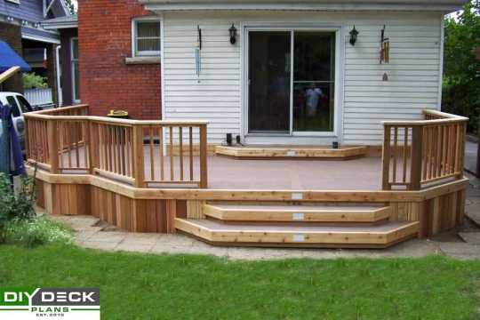 Single level deck with composite deck boards and low voltage lighting attached to a house.