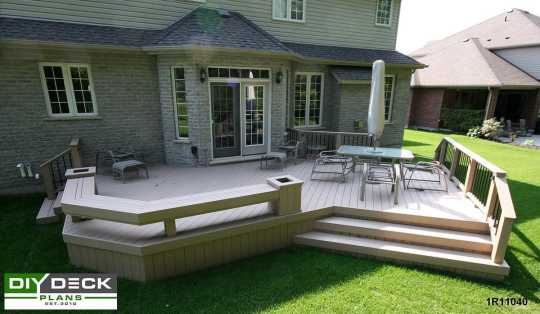 Large composite deck with a bench and planter boxes attached to a grey brick house.