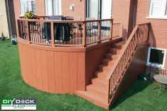 Deck with curved front face attached to a red brick house.