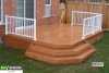 Low single level cedar deck with a white aluminum railing attached to a red brick house.