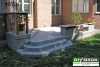 Grey composite deck with planters and a bench attached to a red brick house.