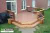 Medium sized deck with black aluminum railing and planters attached to a red brick house.