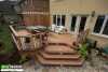 Brown composite deck with a pergola and spa attached to a stucco house.